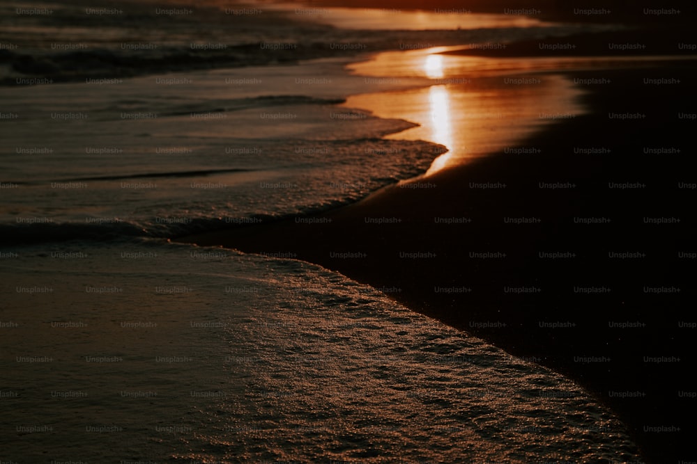 o sol está se pondo sobre a água na praia