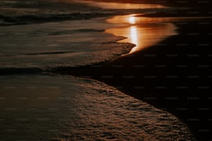 the sun is setting over the water at the beach