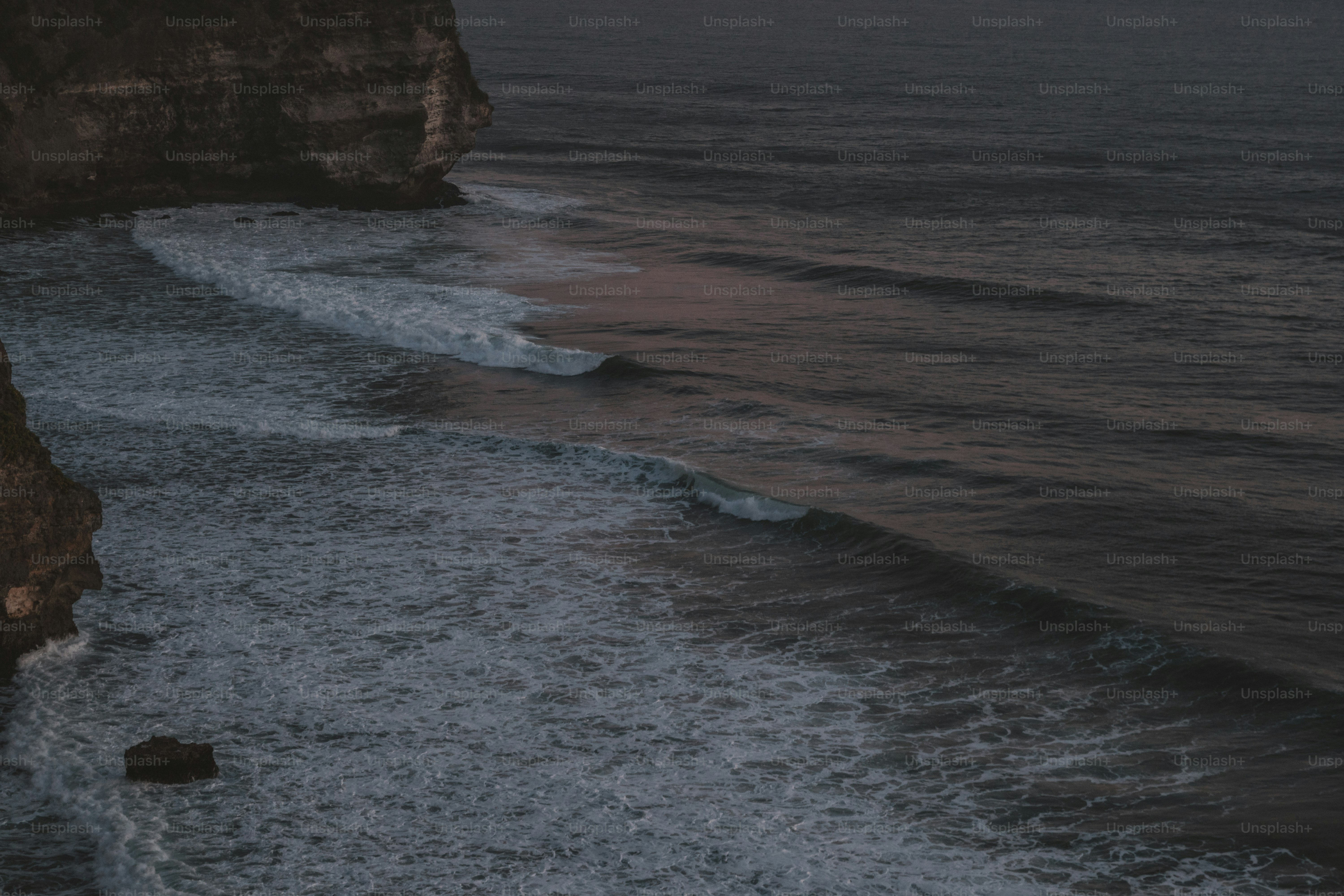 a couple of people standing on top of a cliff next to the ocean