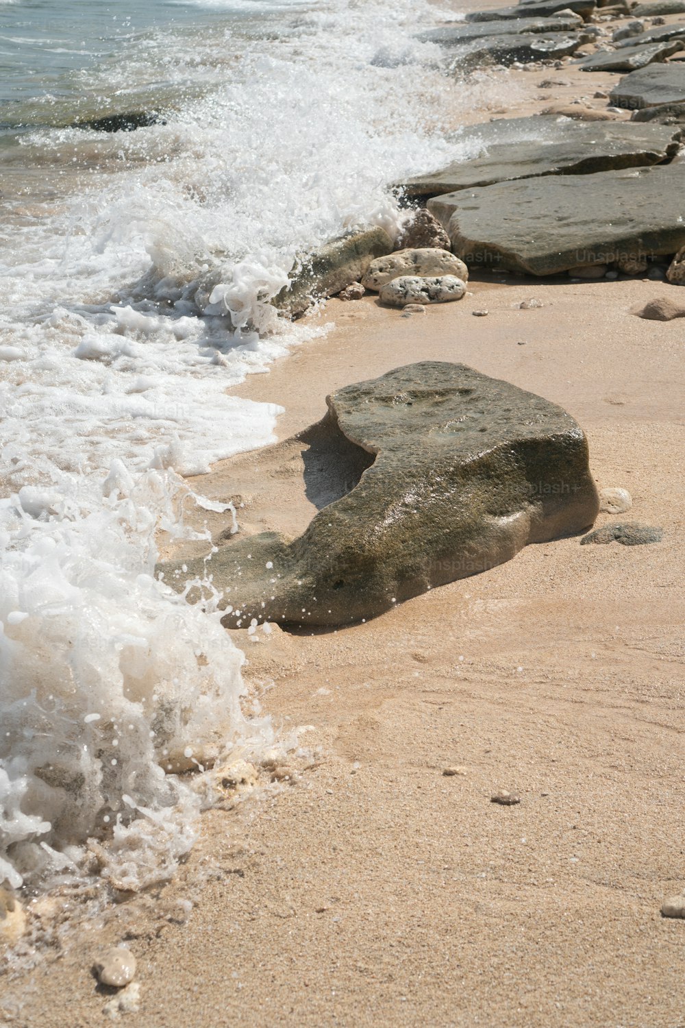 a rock laying on the beach next to the ocean