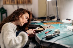 Stock photo of concentrated woman working in jewelry workshop.
