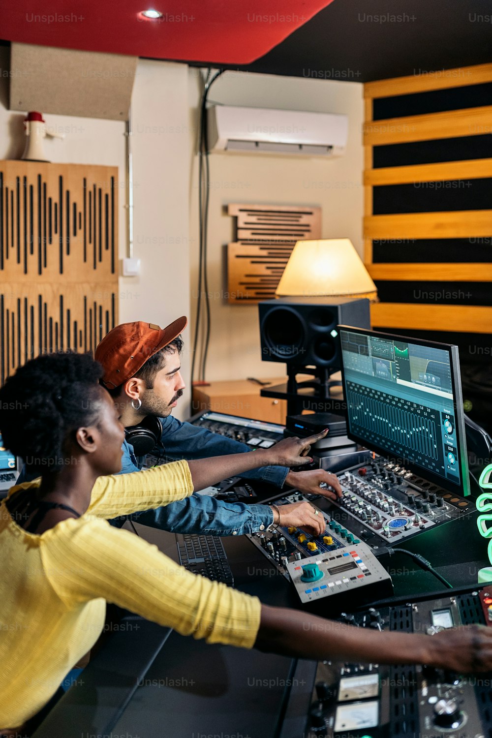 Stock photo of happy black singer working in professional music studio with young music producer.