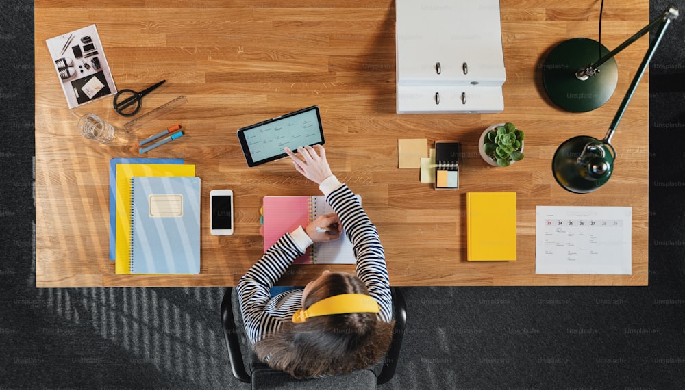 Una vista superior de una estudiante trabajando en la computadora en el escritorio de casa.