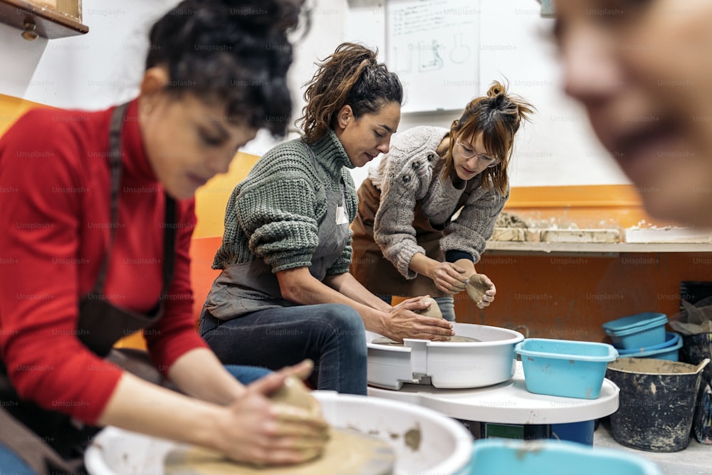 陶芸の先生が集中した女性に糸車の使い方を説明するストックフォト。