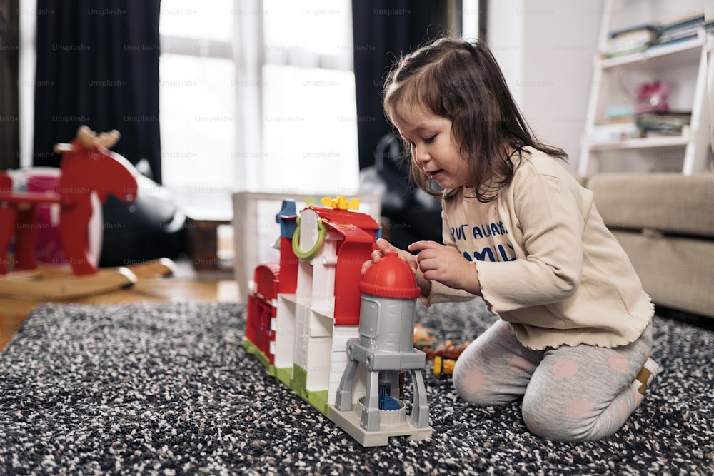 Stockfoto eines süßen kleinen Mädchens, das Spaß zu Hause hat, um mit ihren Spielsachen zu spielen.