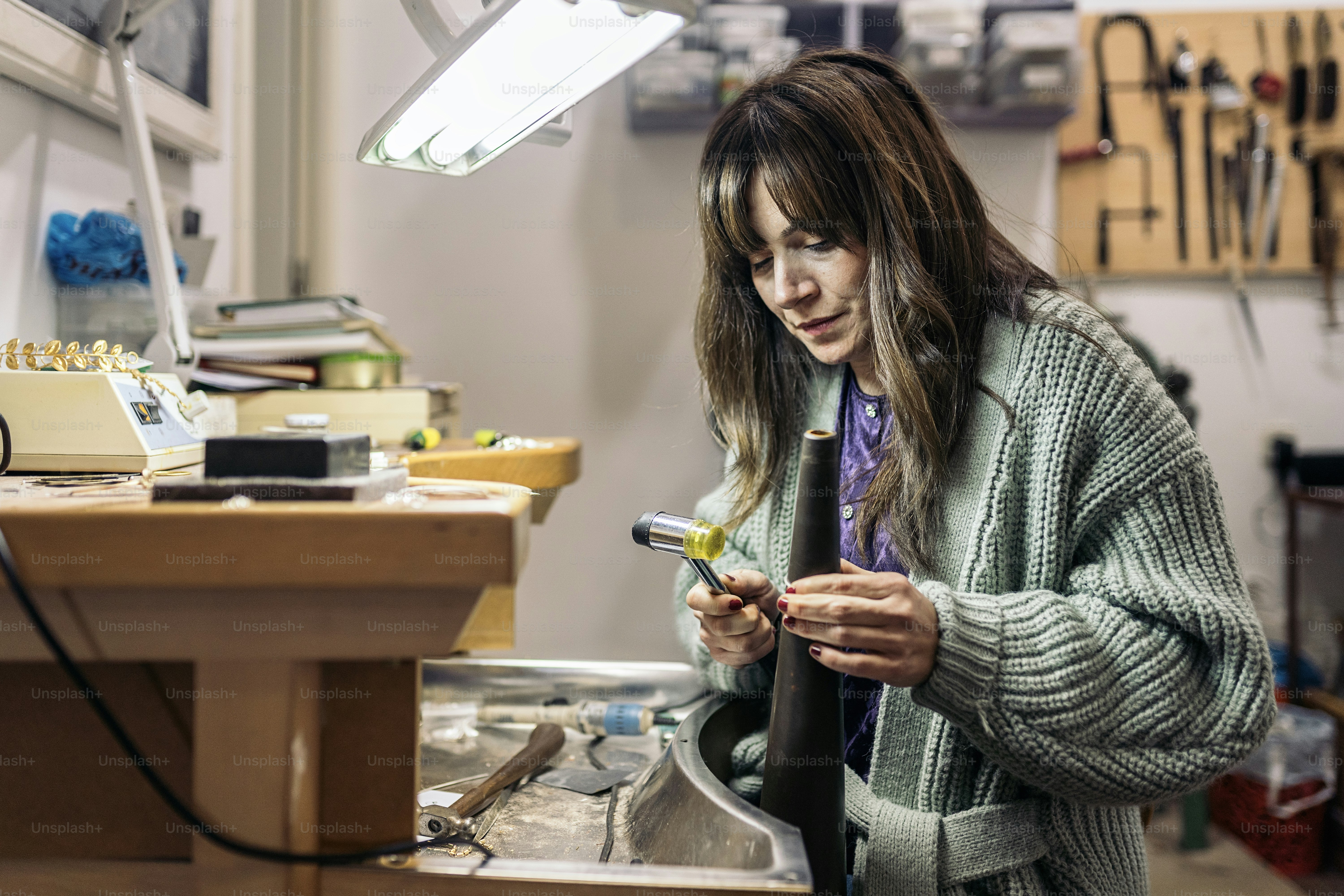 Concentrated woman using special tools in jewelry workshop.