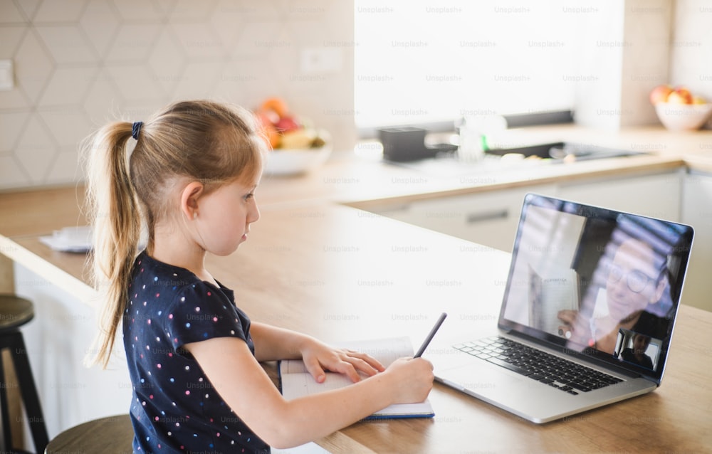 집에서 인터넷을 통해 노트북을 배우는 작은 소녀, 코로나 바이러스 및 격리 개념.