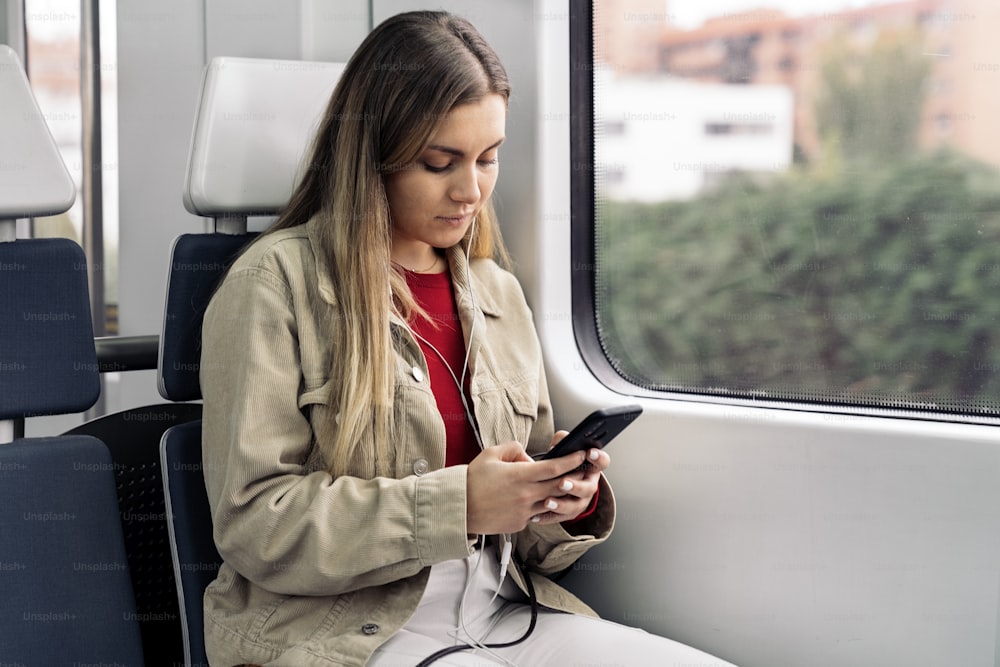 Stock photo of young attractive girl listening to music wearing headphones and looking at her phone.