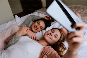 Gorgeous friends taking a selfie in the bedroom. Best friend concept.