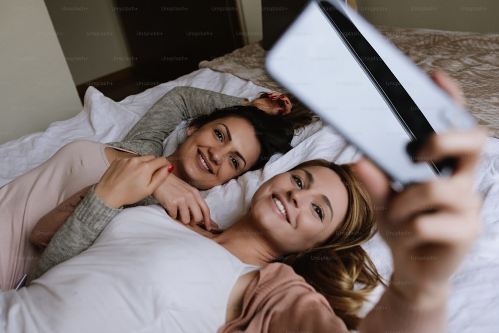 Gorgeous friends taking a selfie in the bedroom. Best friend concept.