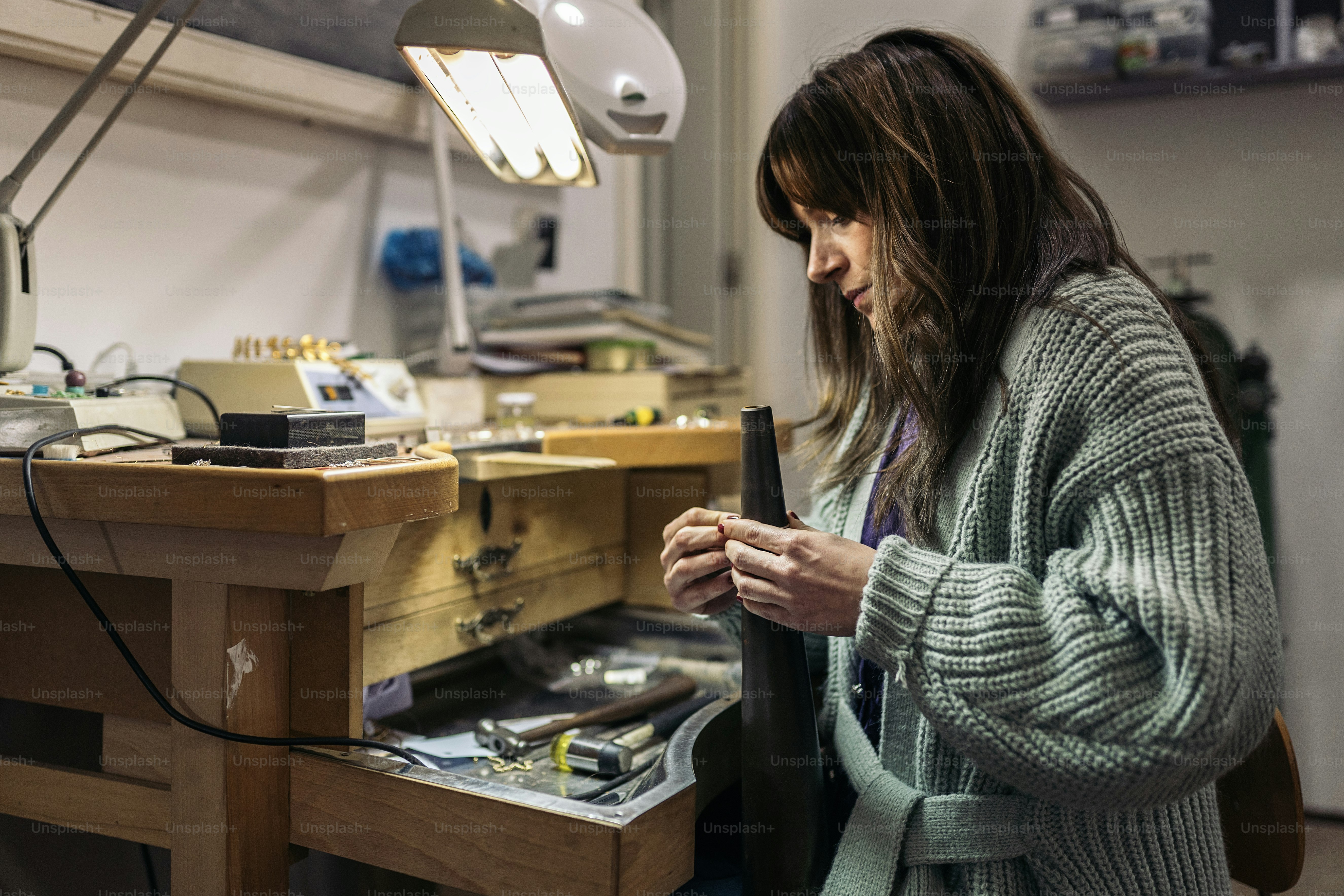 Stock photo of concentrated woman working in jewelry workshop.