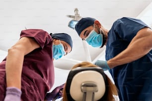 Archivfoto von Arbeitern einer Zahnklinik, die während einer Untersuchung Uniformen mit einem Patienten tragen.