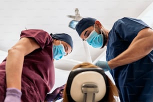 Foto de archivo de trabajadores de una clínica dental vistiendo uniformes con un paciente durante un chequeo.