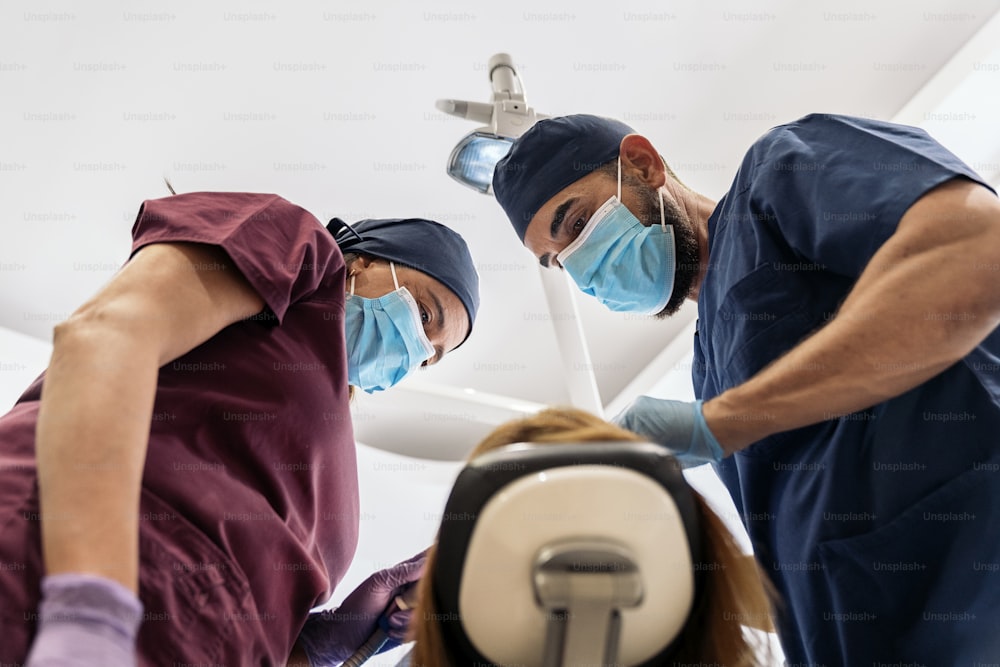 Stock photo of workers of a dental clinic wearing uniforms with a patient during a checkup.