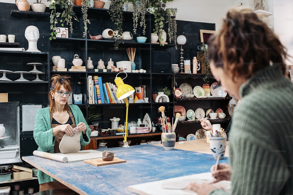 Banque d’images - femme heureuse en tablier travaillant dans un atelier de poterie.