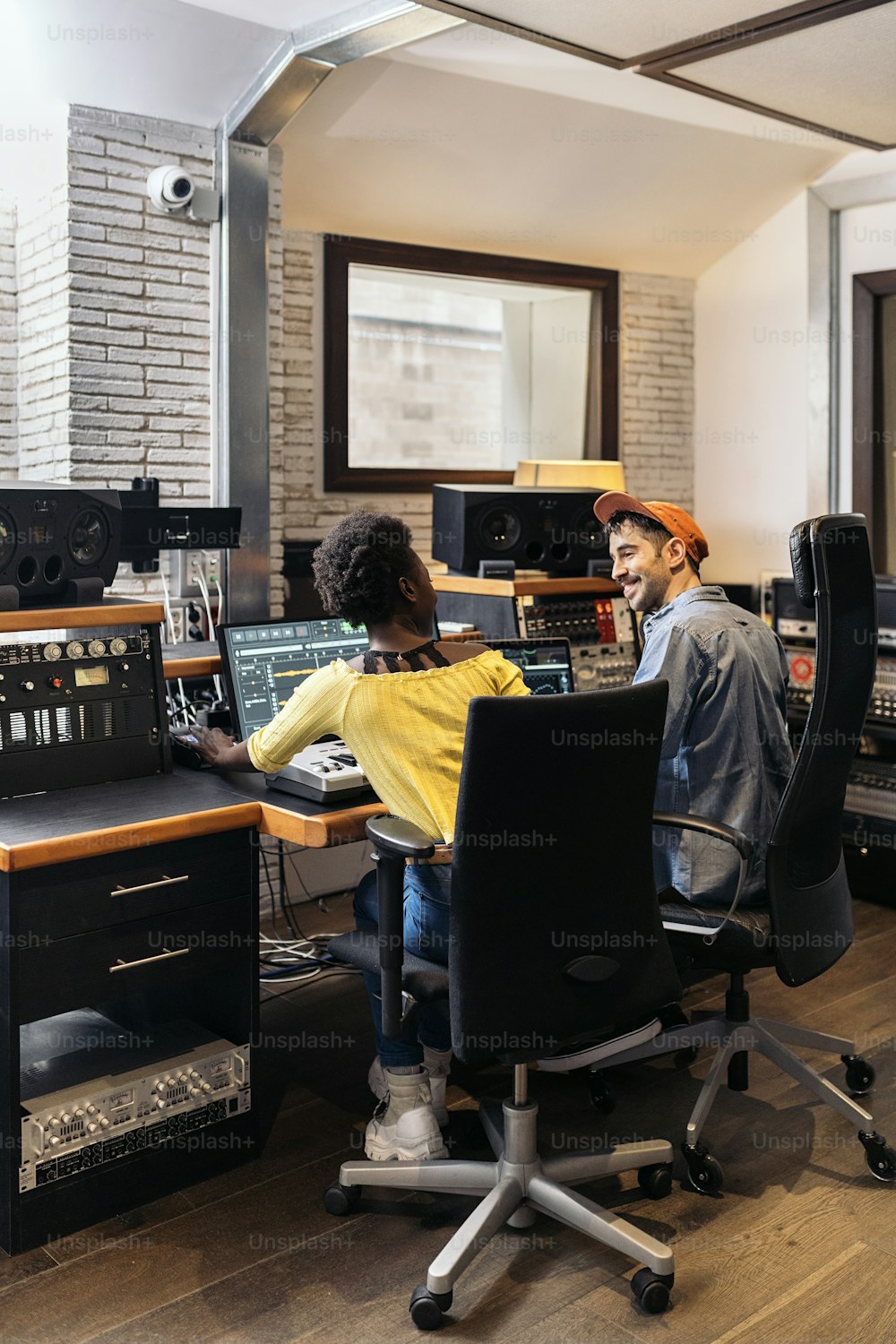 Stock photo of black woman working with male producer in music studio.