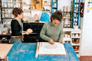 Foto de archivo de mujer feliz en delantal trabajando en taller de cerámica y usando arcilla.