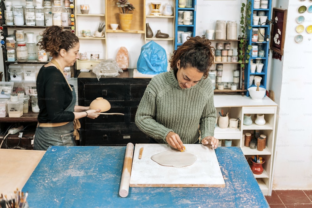 Banque d’images - femme heureuse en tablier travaillant dans un atelier de poterie et utilisant de l’argile.