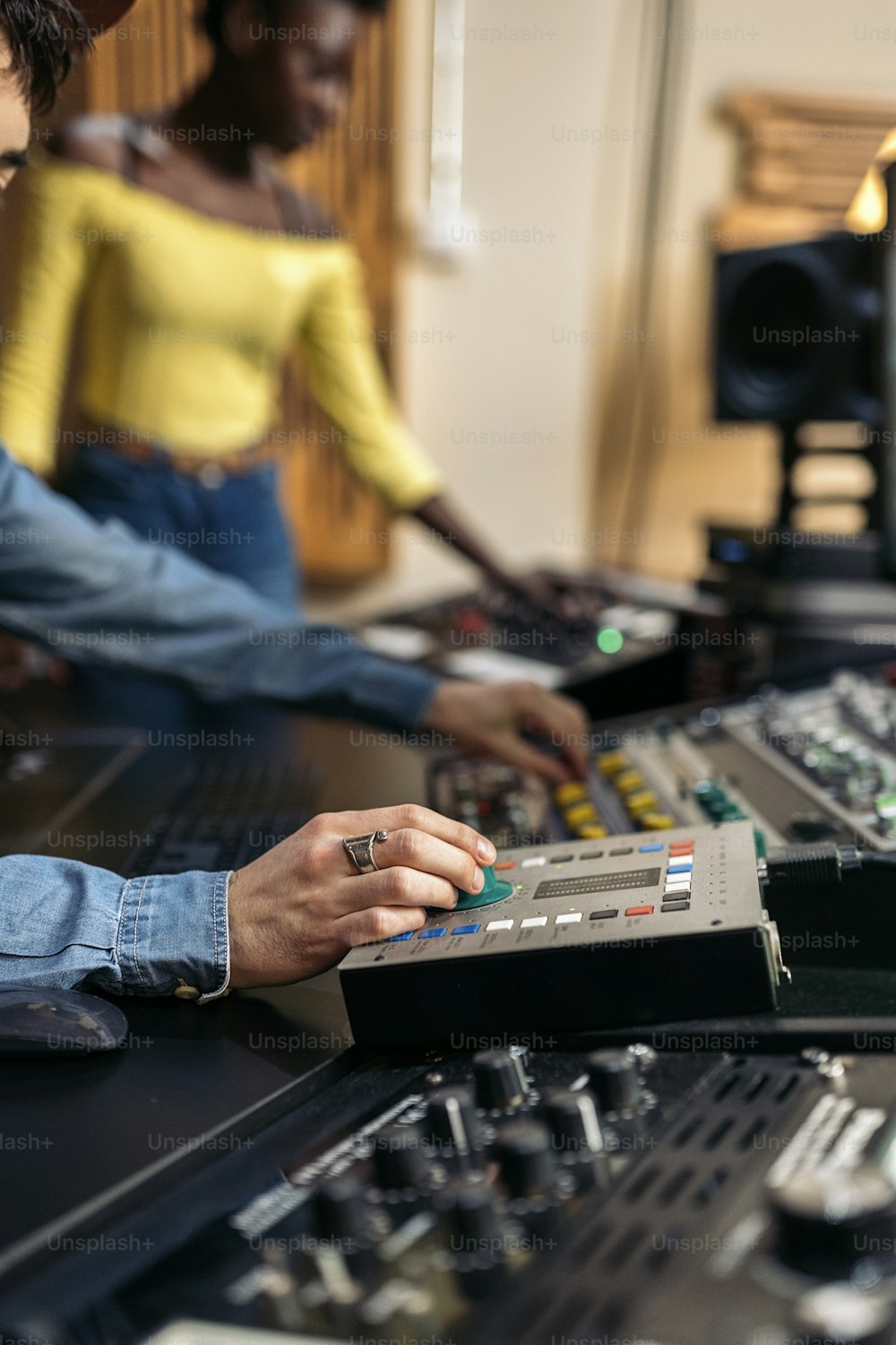 Stock photo of unrecognized male music producer working with black singer in professional music studio.