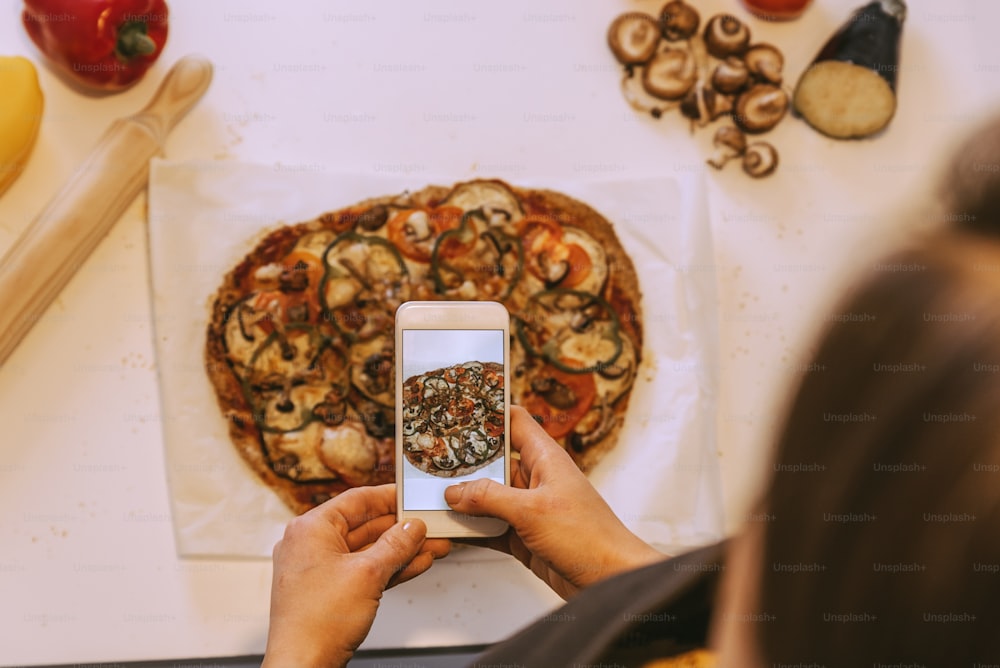 Woman taking picture to delicious pizza. Home made concept.