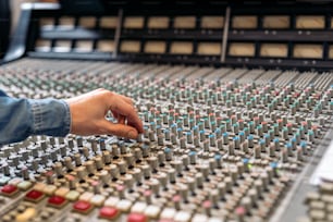 Stock photo of unrecognized person using panel control in professional music studio.