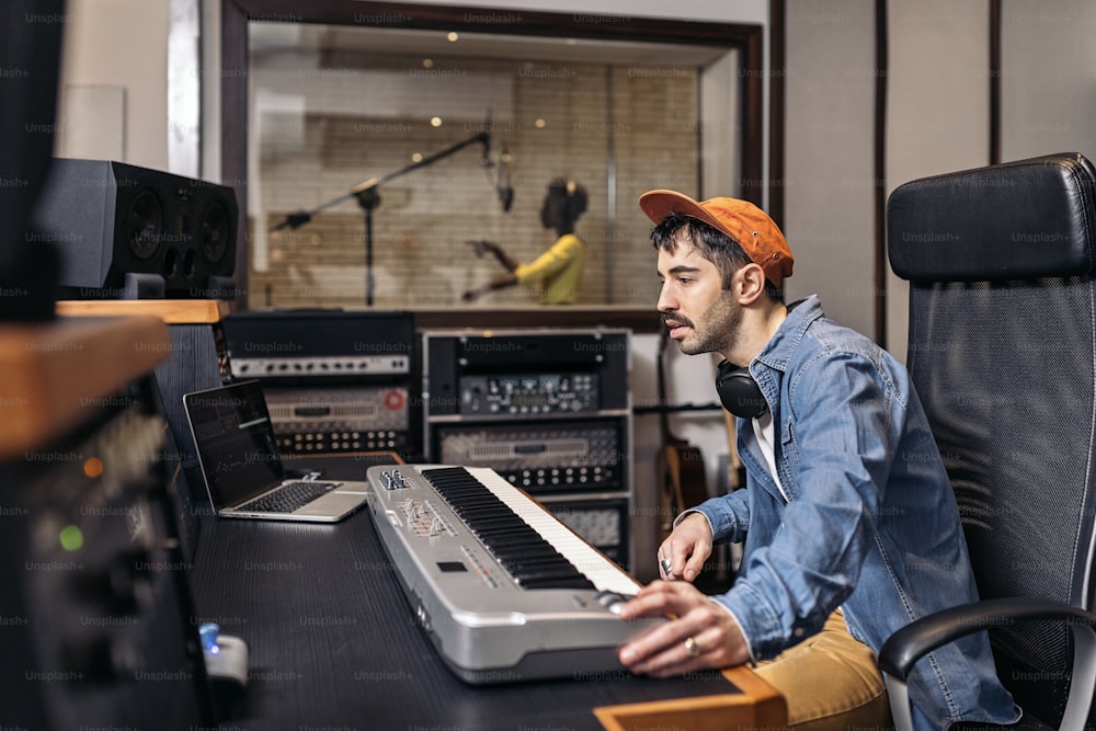 Stockfoto eines männlichen Musikproduzenten, der mit einem schwarzen Sänger in einem coolen Musikstudio arbeitet.
