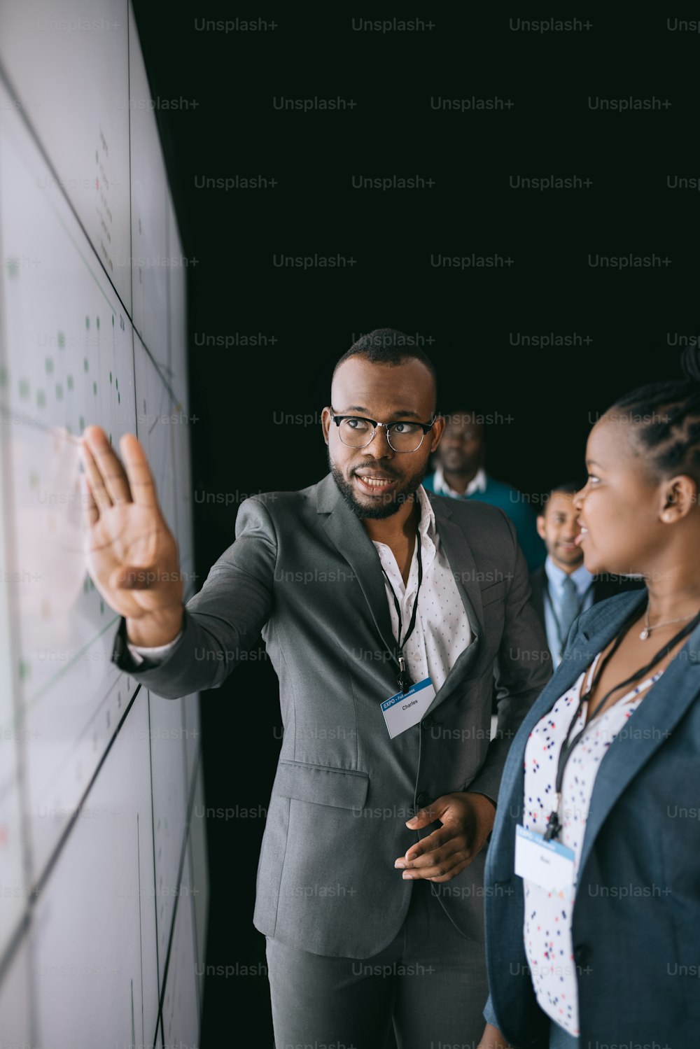 Hombre de negocios africano negro señalando y mirando una gran pantalla de video para una presentación durante una conferencia.