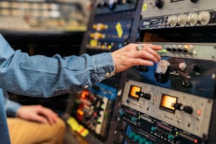 Stock photo of unrecognized person using panel control in professional music studio.