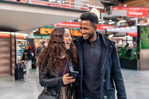 기차역에서 전화를 사용하는 연인의 다른 인종 커플의 행복한 순간의 스톡 사진. 그들은 마드리드 시내에 있습니다.