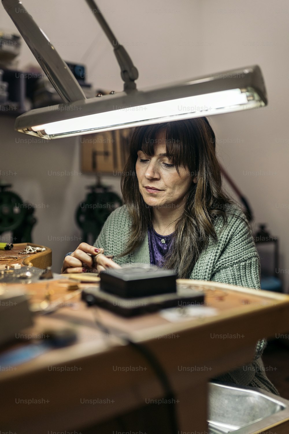 Stock photo of concentrated woman working in jewelry workshop.