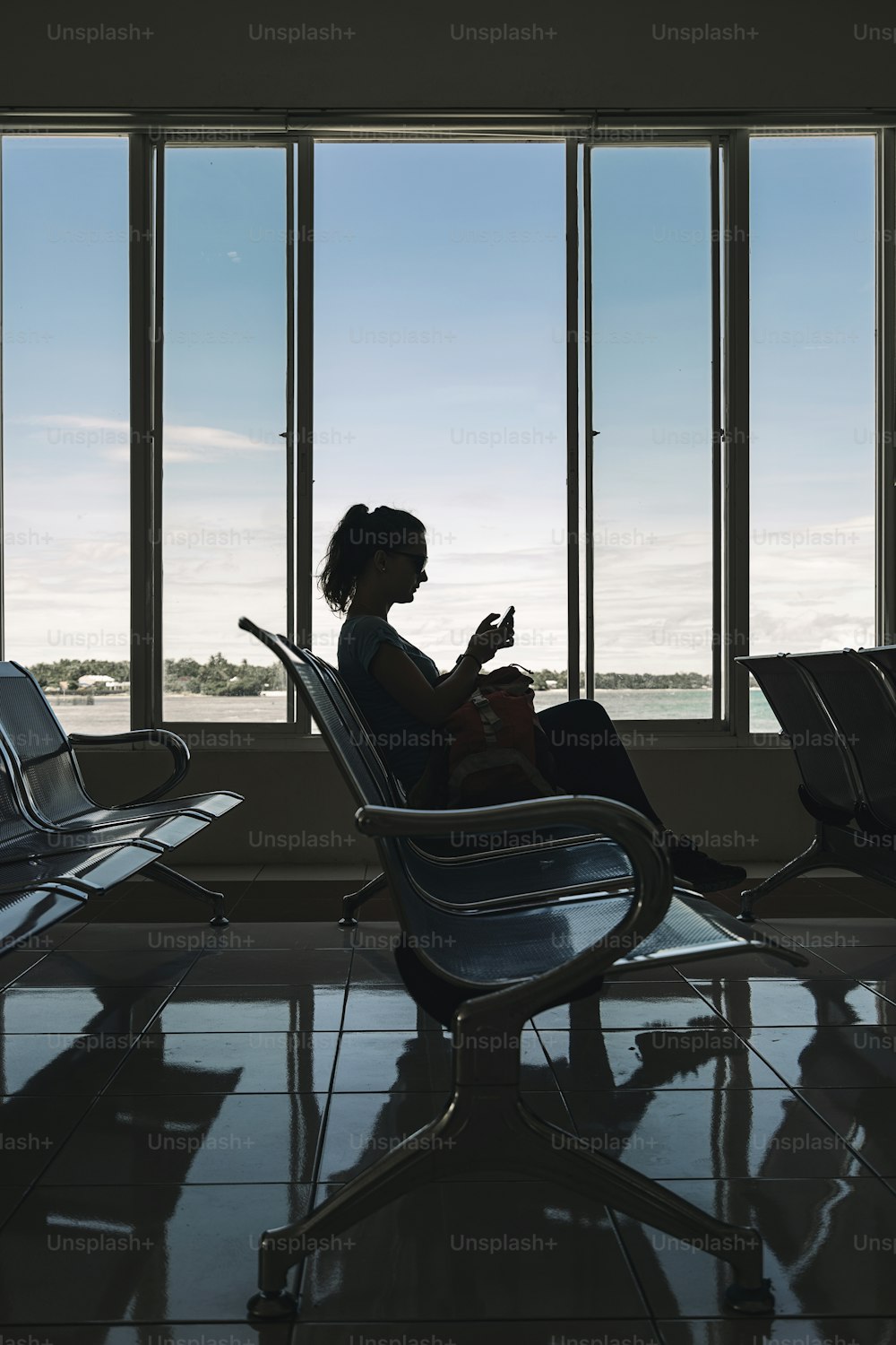 Nicht erkennbare Frau, die am Flughafen wartet, während sie ihr Smartphone benutzt. Reisekonzept