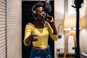 Banque d’images d’une belle femme noire chantant et utilisant un microphone dans un studio de musique.