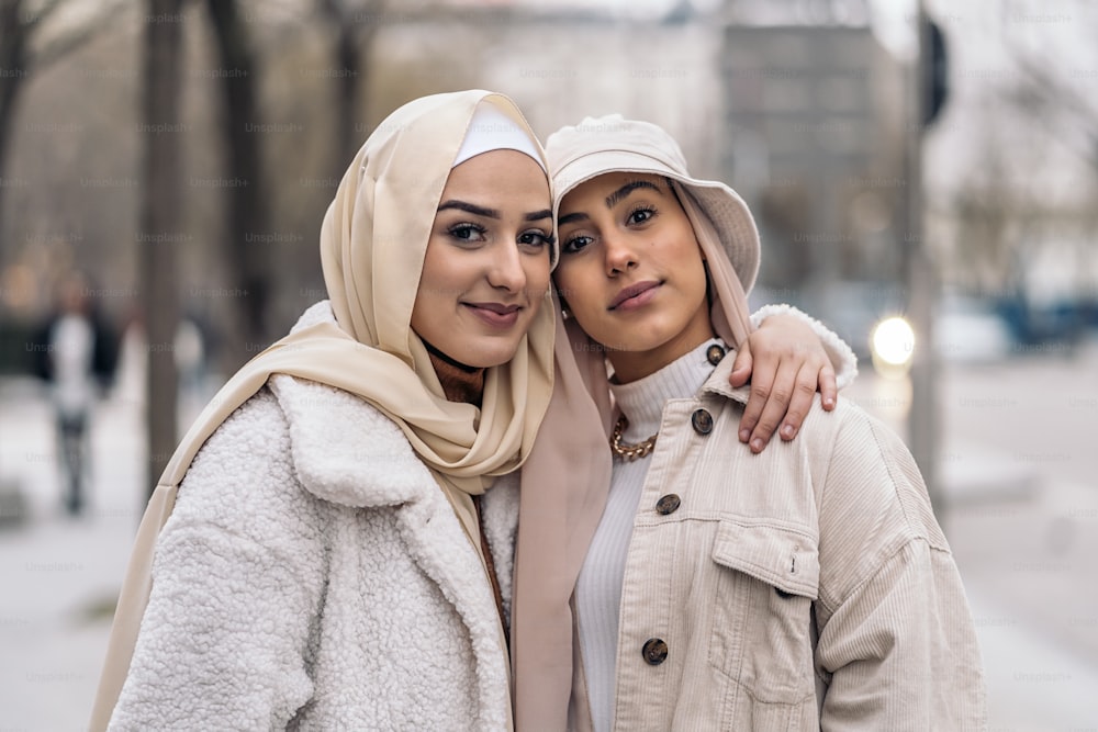 Smiley muslim women wearing head scarf posing and looking at camera in the street.