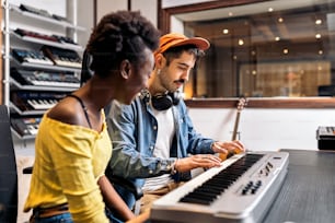 Stock photo of black woman playing electronic piano keyboard in music studio.