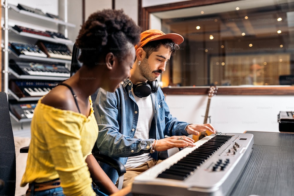 Stockfoto einer schwarzen Frau, die im Musikstudio elektronische Klaviertastatur spielt.