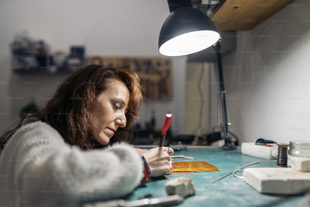 Femme adulte concentrée travaillant dans un atelier de bijouterie.