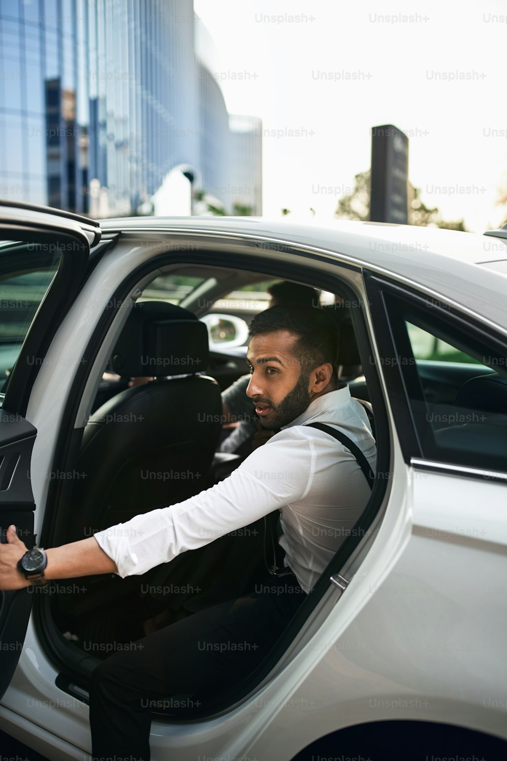 Indian commuter getting out of a taxi. Businessman exiting a taxi wearing smart suit with suspenders