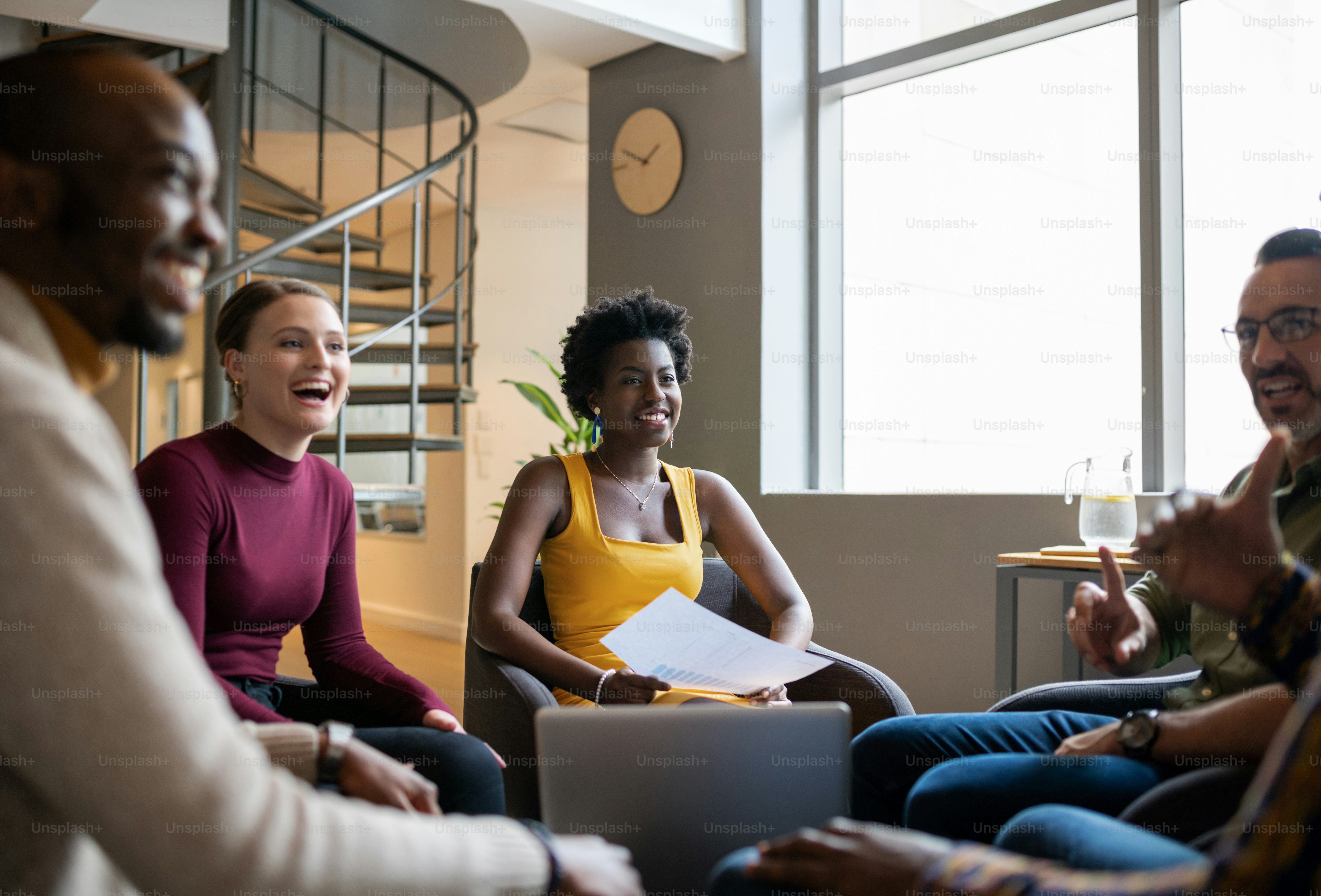 Groupe diversifié d’hommes d’affaires rieurs assis ensemble dans le salon d’un bureau et discutant de leur travail