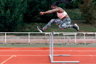 Foto de archivo de un velocista afroamericano saltando una valla en el centro deportivo