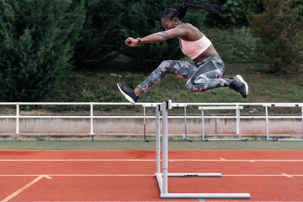 Stock photo of an African-American sprinter jumping a hurdle in the sports center