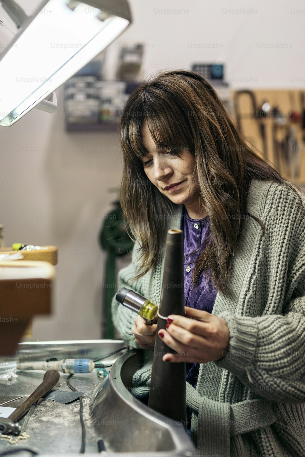 Concentrated woman using special tools in jewelry workshop.