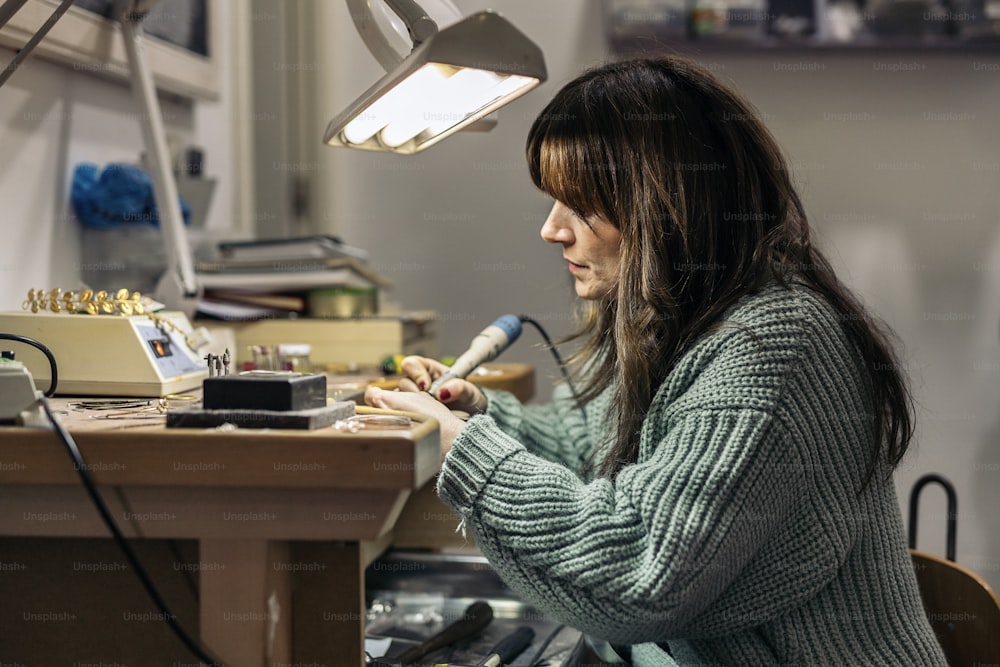 Mujer adulta concentrada trabajando en taller de joyería.