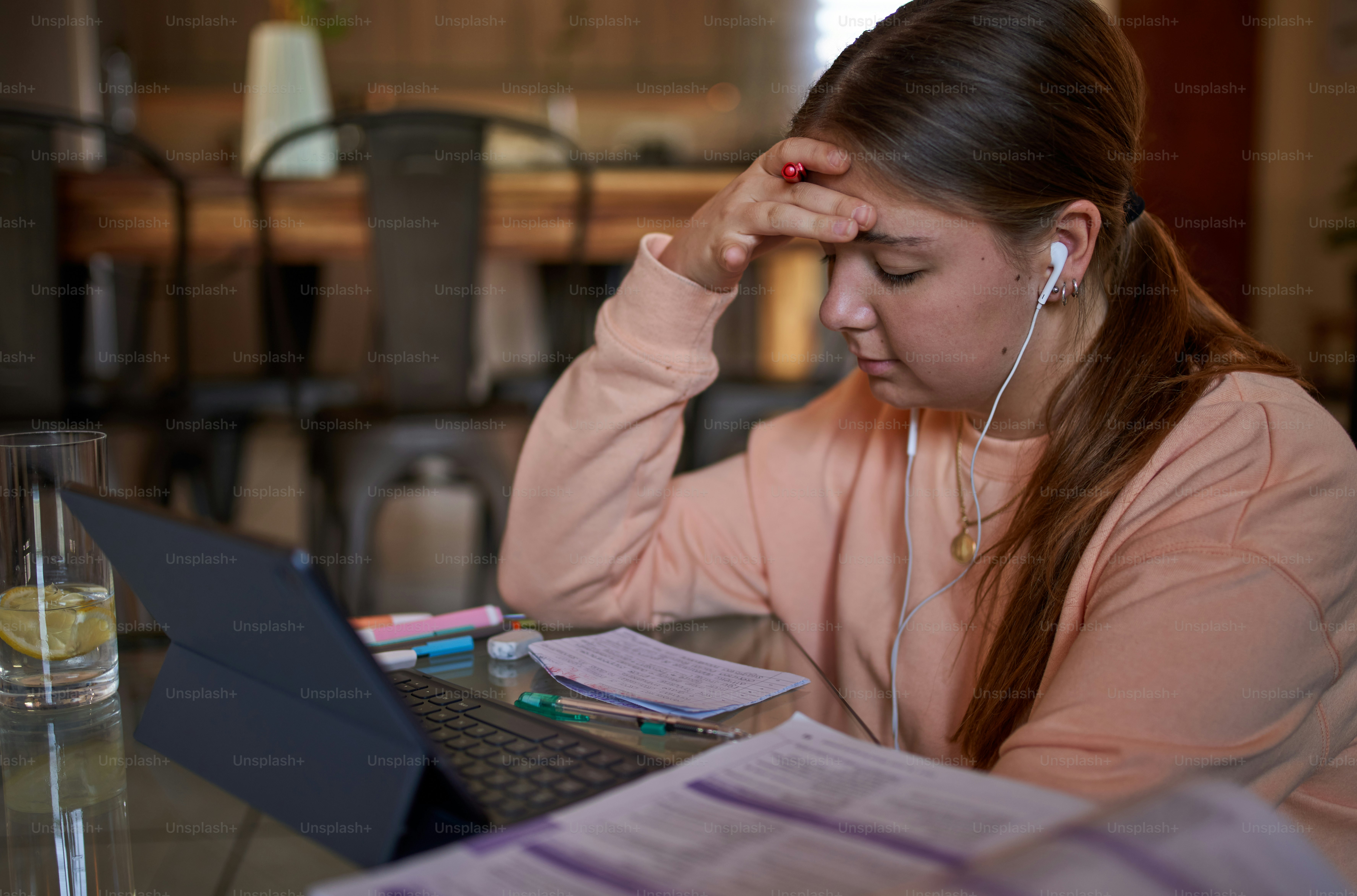 Portrait of young teenage school girl sitting at coffee table listening to music, using earphones in modern cozy living room interior, studying and relaxing at home. Online education and elearning concept during quarantine