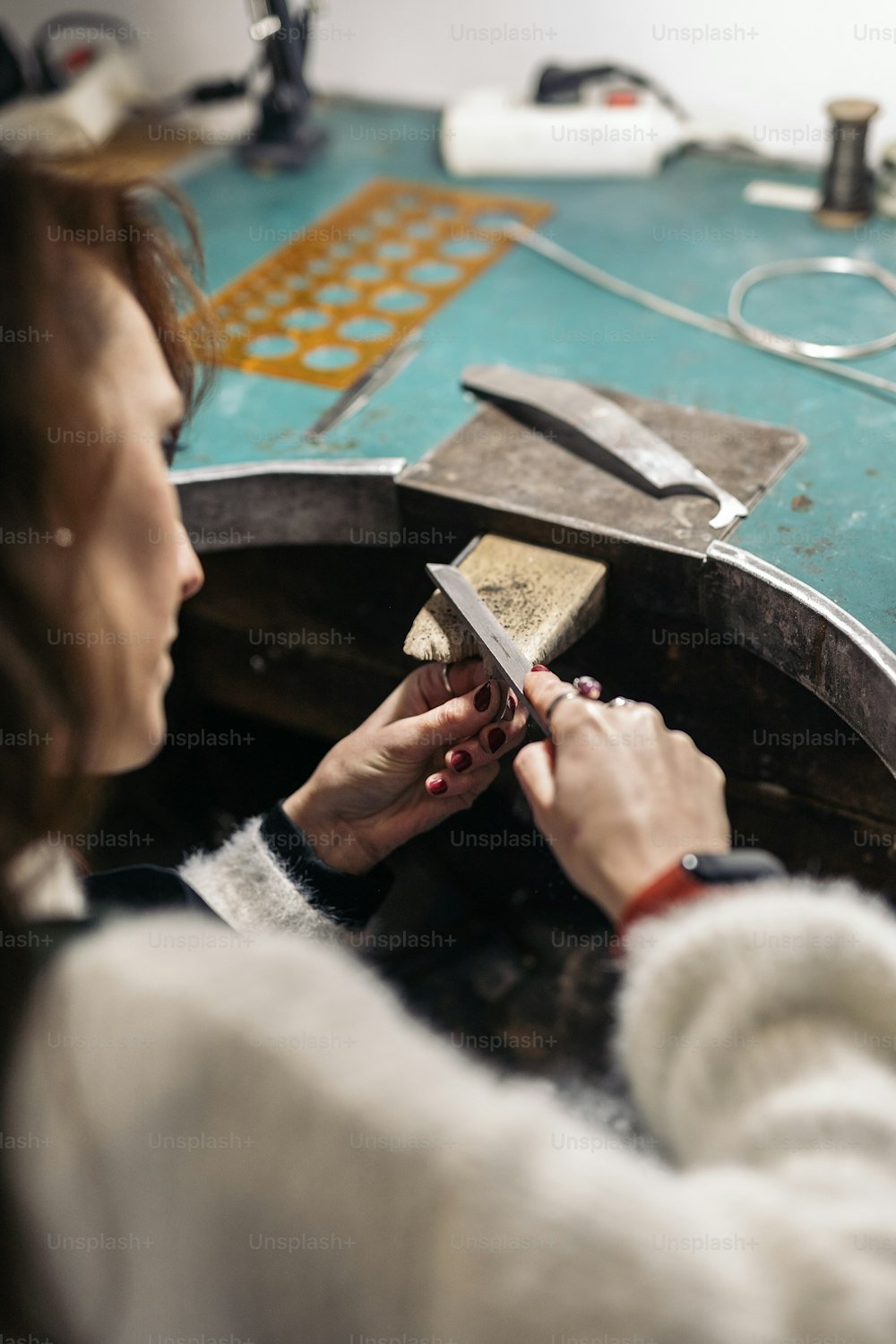 Mujer adulta concentrada trabajando en taller de joyería.