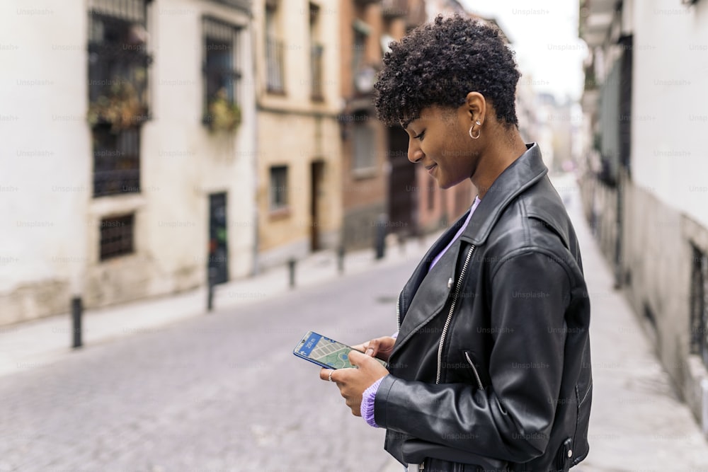 Stock photo of young afro woman looking at a map in her phone.