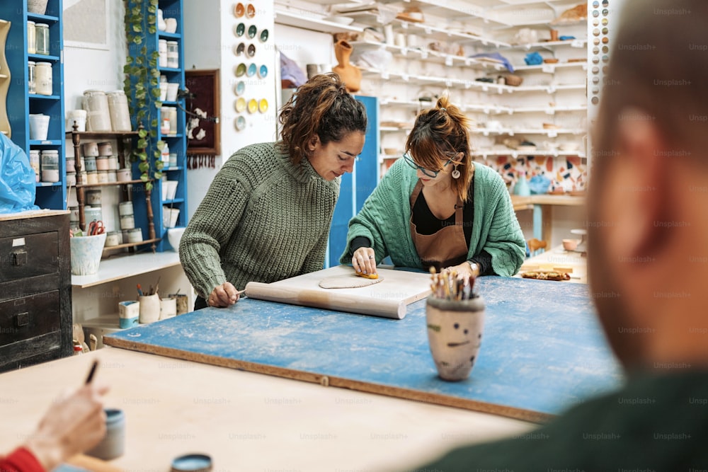 Banque d’images de femmes concentrées en tablier travaillant dans un atelier de poterie.