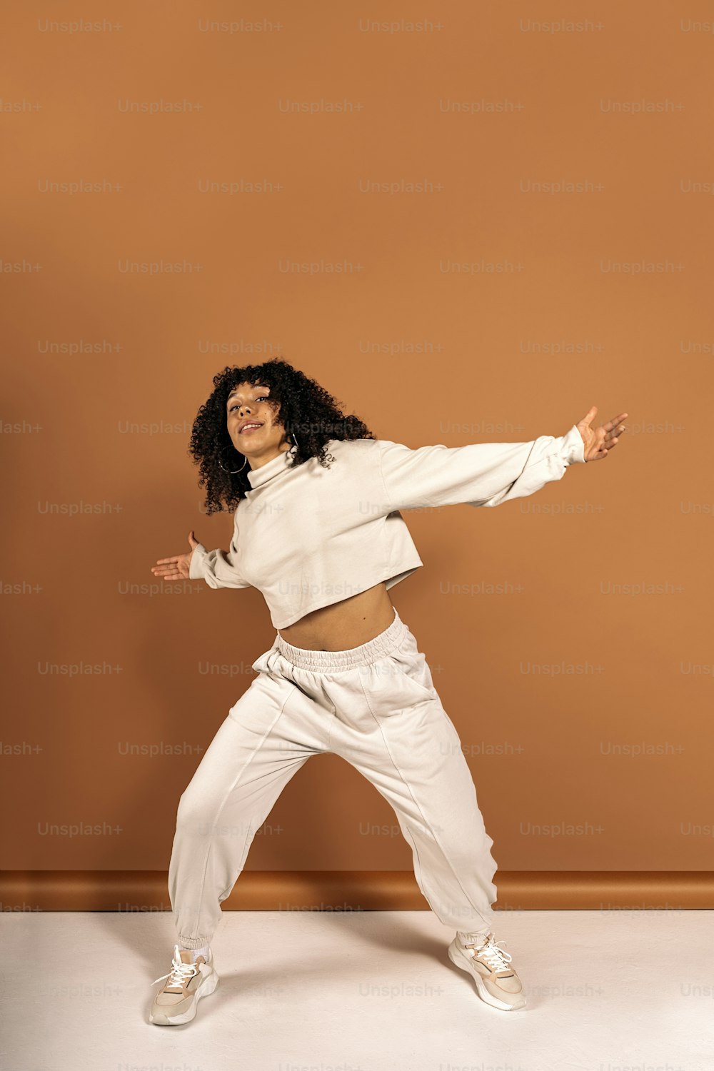茶色の背景を背景にスタジオで撮影したクールなアフリカ系アメリカ人ダンサーのポーズの写真。