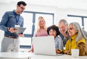 Grupo de alegres personas mayores que asisten a la clase de educación informática y tecnológica.