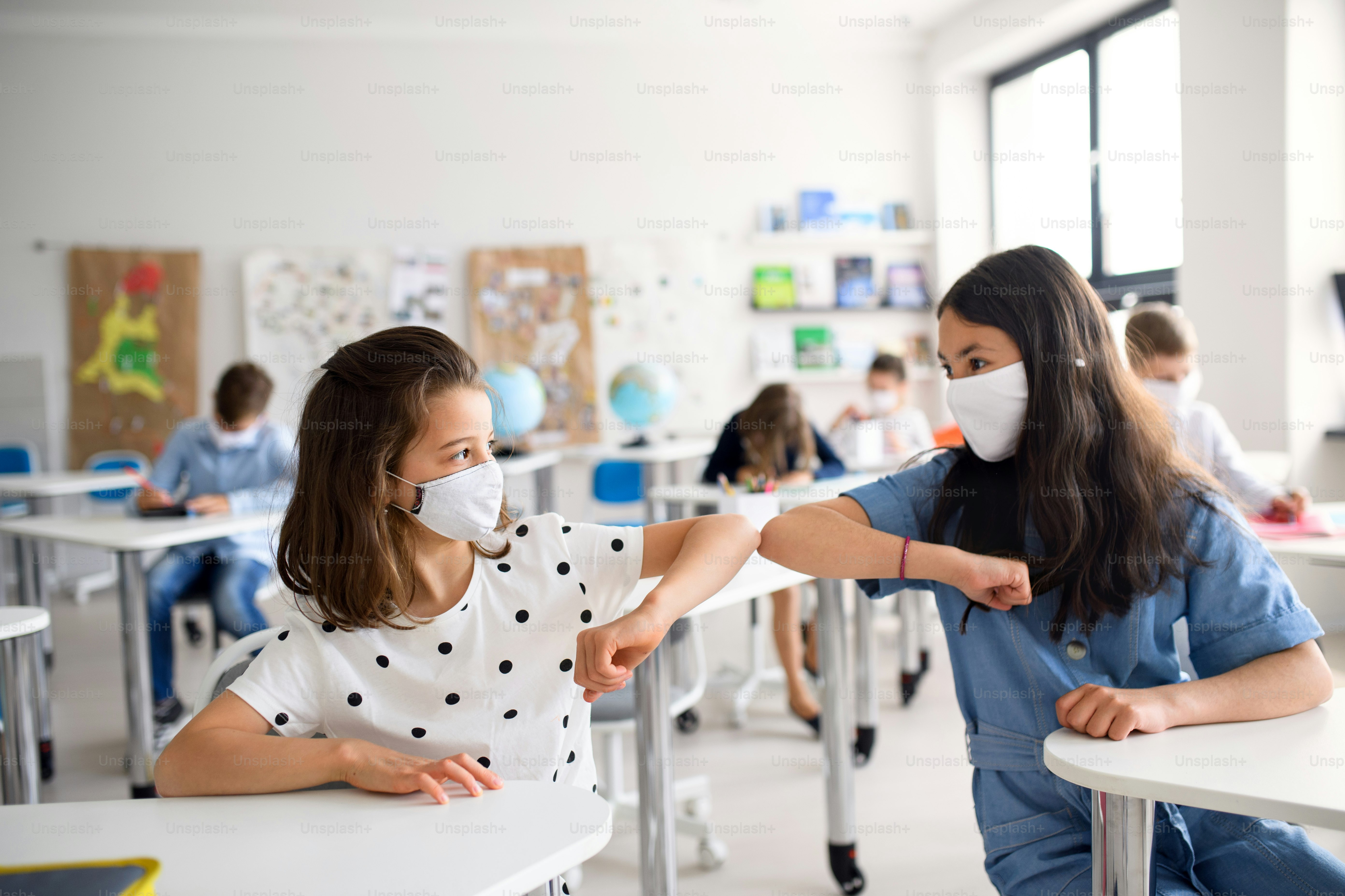 Small children with face mask back at school after covid-19 quarantine and lockdown, greeting