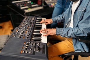 Stock photo of unrecognized musician in professional music studio playing electronic piano keyboard.
